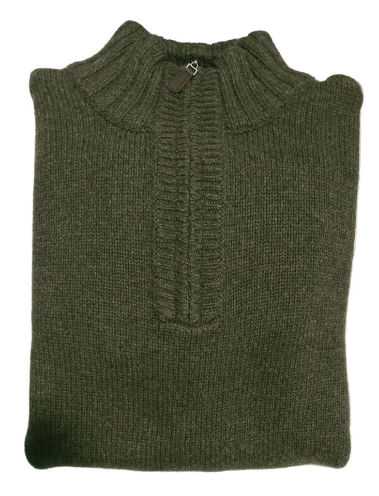 Green sweater on a white surface with a pen and paper underneath