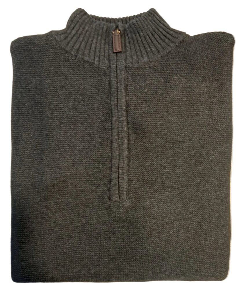 Folded gray sweater on a white surface with a blurred background