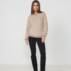Woman wearing a beige sweater and black pants with knee-high boots on a white background