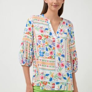 Woman wearing a colorful floral blouse with green pants on a white background