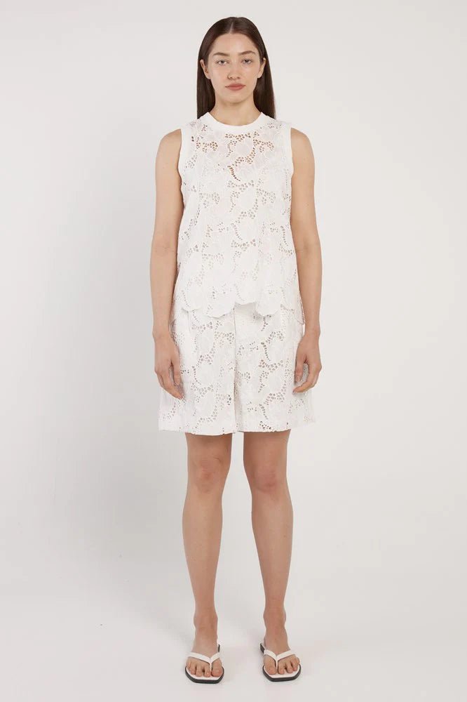 Woman wearing a white floral dress on a plain background