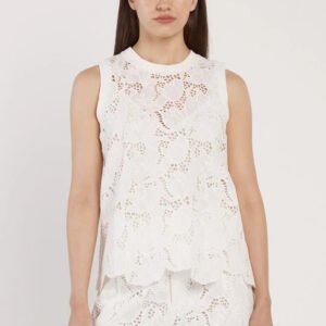 Woman wearing a white sleeveless top with floral lace details on a plain background